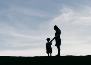Young mother holding her daughter in the sunset