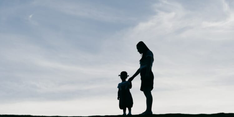 Young mother holding her daughter in the sunset