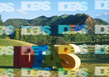 A large colorful letters in a field with mountains in the background