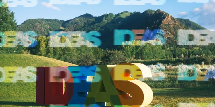 A large colorful letters in a field with mountains in the background