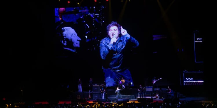 A man on a stage with a large screen