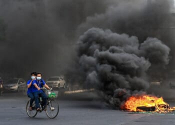 A man and woman riding a bicycle on fire