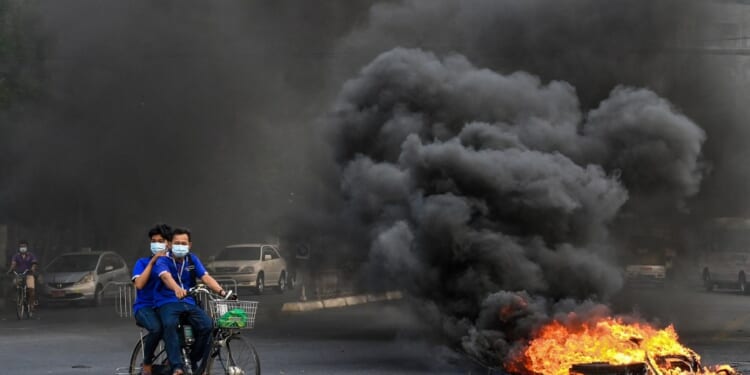 A man and woman riding a bicycle on fire