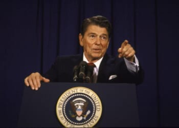 A man in a suit pointing at the camera