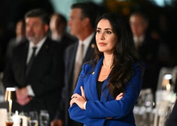 A woman in a blue suit with her arms crossed