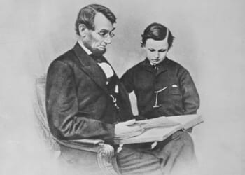 A man and boy sitting in a chair reading a book