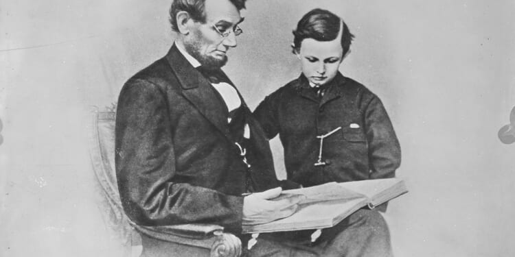 A man and boy sitting in a chair reading a book