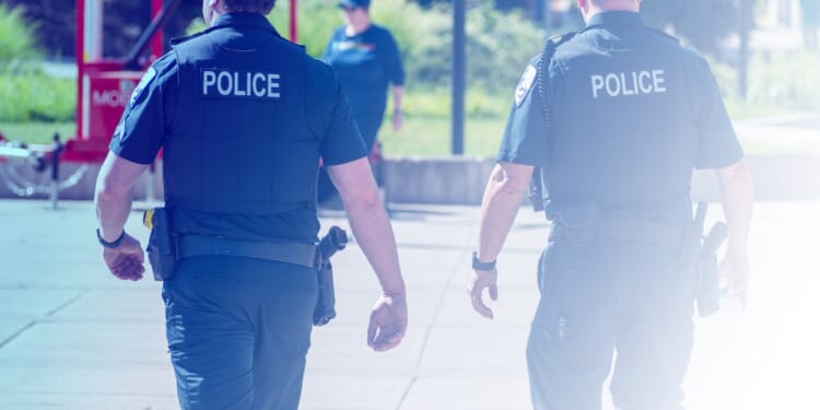 Two police officers walking on a sidewalk