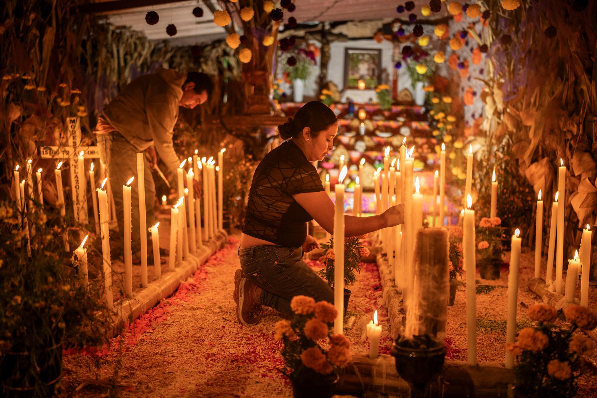 A woman kneeling in front of many candles