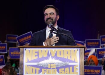 A man in a suit and tie at a podium with a microphone