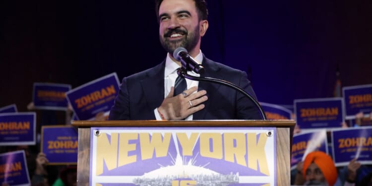 A man in a suit and tie at a podium with a microphone