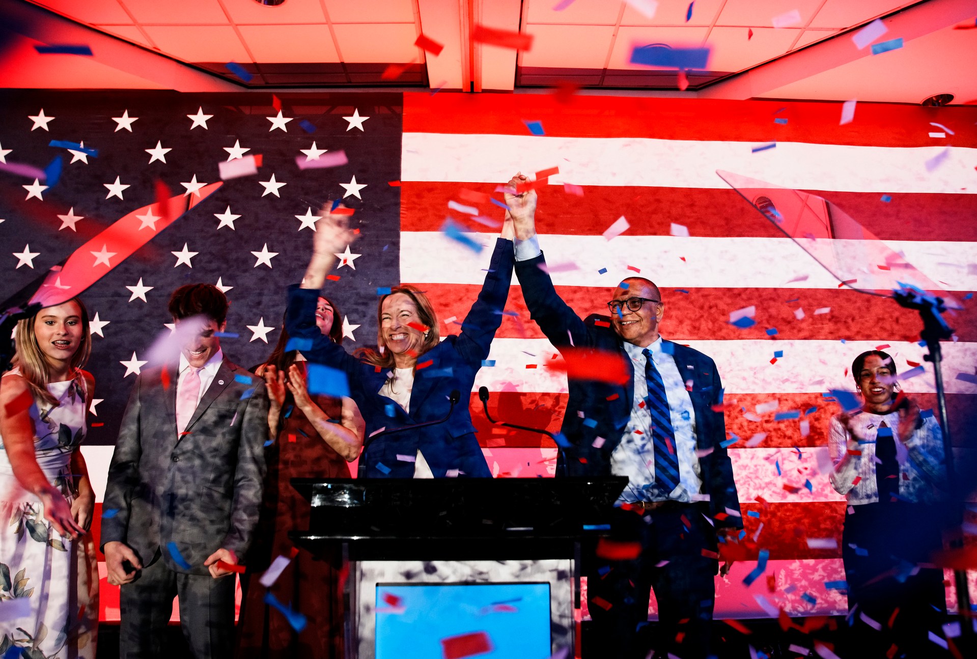 A group of people standing at a podium with confetti falling