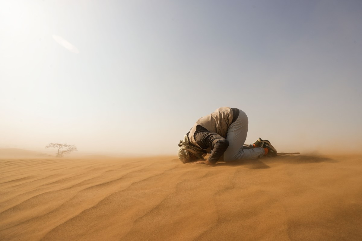 A person lying on the ground in the sand