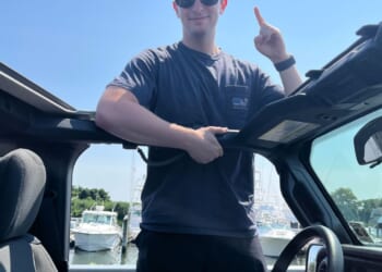 A man in a hat and sunglasses standing in a car
