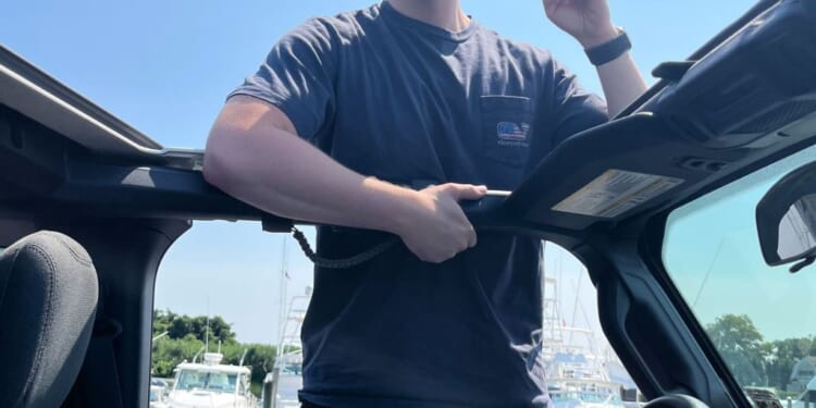 A man in a hat and sunglasses standing in a car
