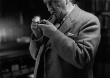 A man in a suit holding a pipe