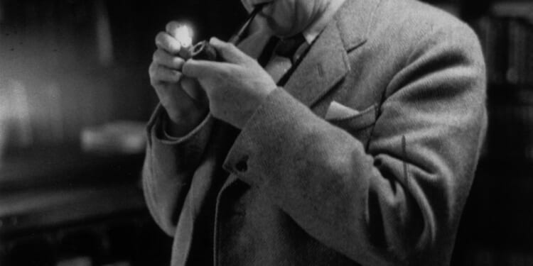 A man in a suit holding a pipe