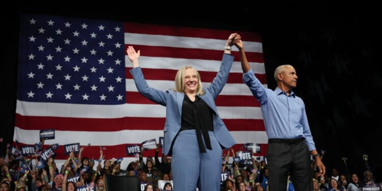 A man and woman holding hands up in front of a flag