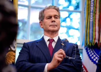 A man in a suit holding glasses