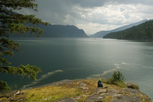 Child sitting near edge of lake