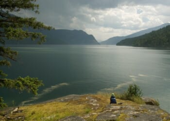 Child sitting near edge of lake
