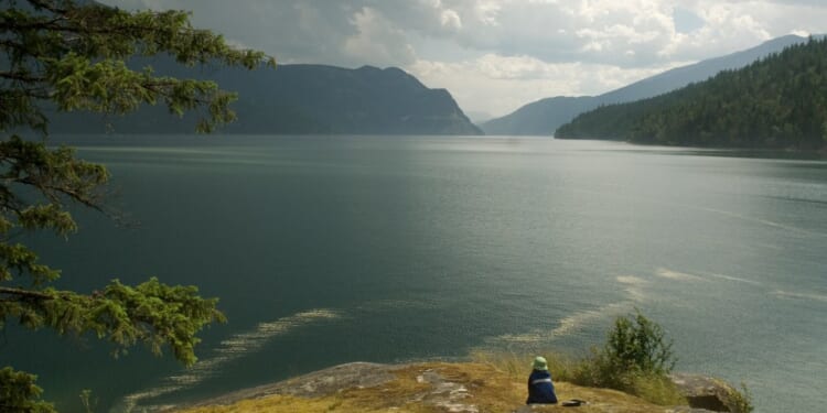 Child sitting near edge of lake