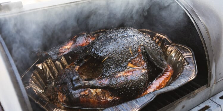 Smoked turkey cooking outdoor on a grill and smoker combination