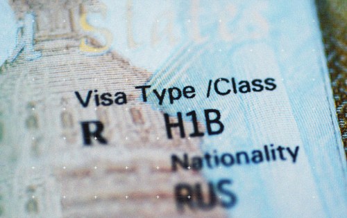 A close-up photograph of a document showing visa information, with "Visa Type/Class" and "H1B" visible along with fields for "Nationality" and other details.