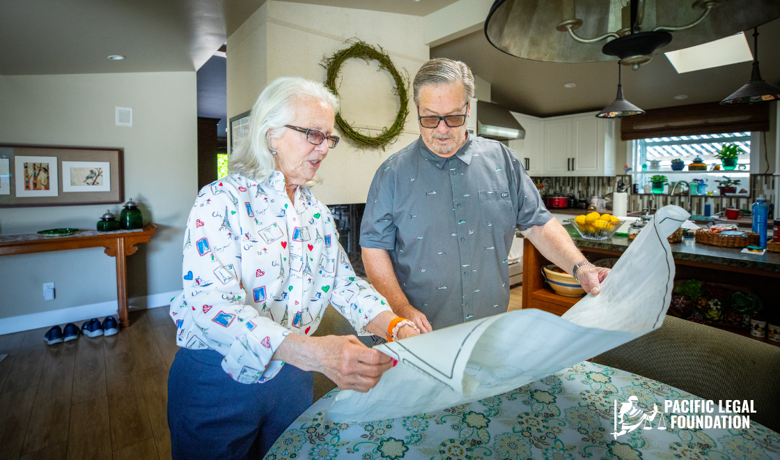 An older woman and man examine documents together at a kitchen counter in a bright, modern home.