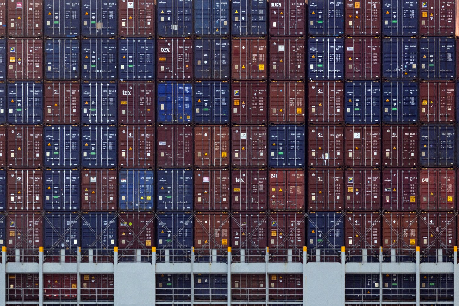 Overhead view of a cargo ship stacked with hundreds of colorful shipping containers in organized rows, showing the scale of maritime freight transportation.